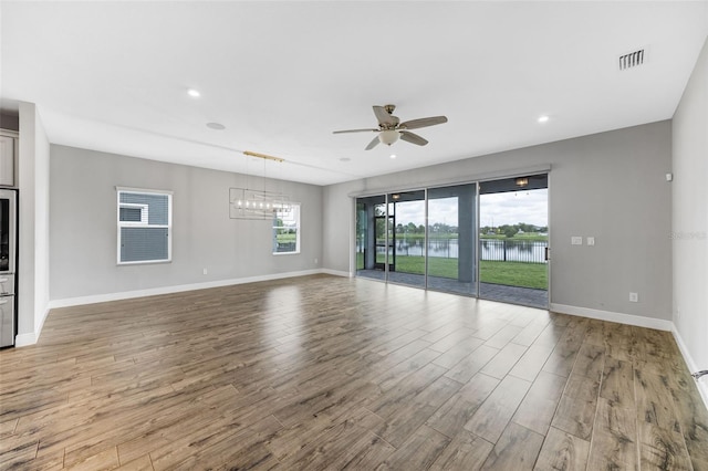 5434 Silver Sun Dr, Apollo Beach, FL 33572 - unfurnished living room with ceiling fan, wood finished floors, a chandelier, a water view, and recessed lighting