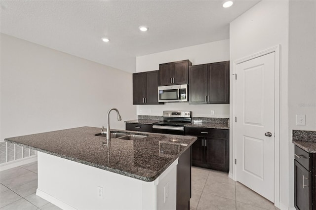 13008 Majestic Garden Ln, Riverview, FL 33579 - kitchen featuring appliances with stainless steel finishes, dark stone counters, an island with sink, light tile patterned flooring, and recessed lighting