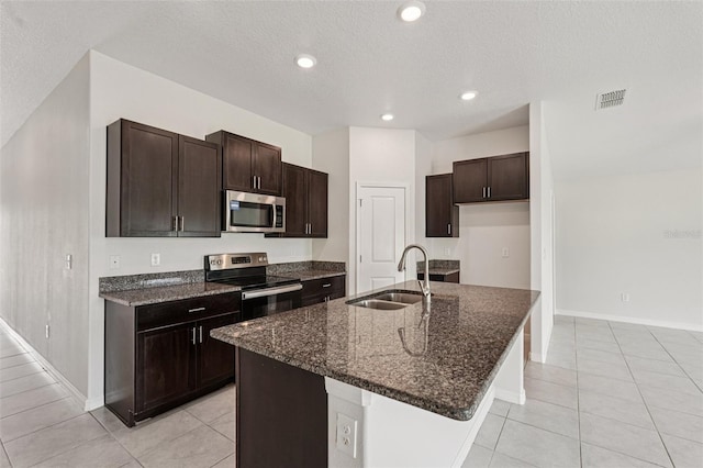 13008 Majestic Garden Ln, Riverview, FL 33579 - kitchen featuring appliances with stainless steel finishes, dark stone counters, light tile patterned floors, dark brown cabinetry, and recessed lighting