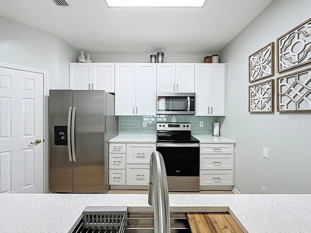 2300 Butterfly Palm Way Unit 204, Kissimmee, FL 34747 - kitchen featuring stainless steel appliances, white cabinetry, tasteful backsplash, and light stone countertops