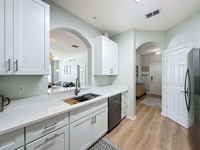 2300 Butterfly Palm Way Unit 204, Kissimmee, FL 34747 - kitchen featuring arched walkways, dishwashing machine, light wood-style floors, freestanding refrigerator, and white cabinets