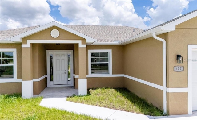 437 Mercedes Ct, Lehigh Acres, FL 33972 - view of exterior entry featuring stucco siding and roof with shingles