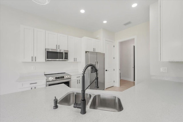 437 Mercedes Ct, Lehigh Acres, FL 33972 - kitchen with appliances with stainless steel finishes, white cabinets, recessed lighting, and light stone countertops