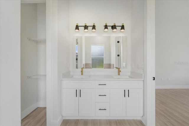 437 Mercedes Ct, Lehigh Acres, FL 33972 - bathroom featuring wood finished floors, double vanity, and a spacious closet