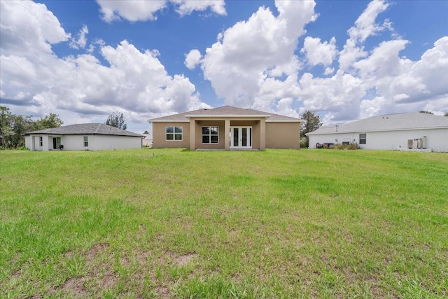 437 Mercedes Ct, Lehigh Acres, FL 33972 - back of property with french doors, a lawn, and stucco siding