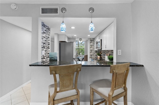 809 Russell Ln Unit 321, Brandon, FL 33510 - kitchen with stainless steel appliances, tasteful backsplash, white cabinetry, decorative light fixtures, and light tile patterned floors