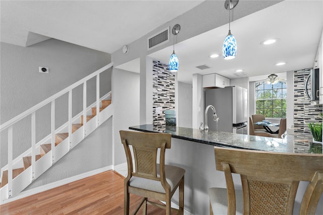 809 Russell Ln Unit 321, Brandon, FL 33510 - kitchen with appliances with stainless steel finishes, light wood-style floors, white cabinetry, hanging light fixtures, and dark stone countertops