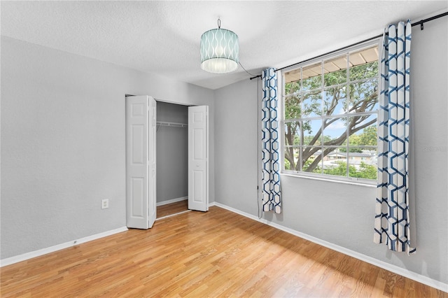809 Russell Ln Unit 321, Brandon, FL 33510 - unfurnished bedroom featuring light wood finished floors, multiple windows, a closet, and a textured ceiling