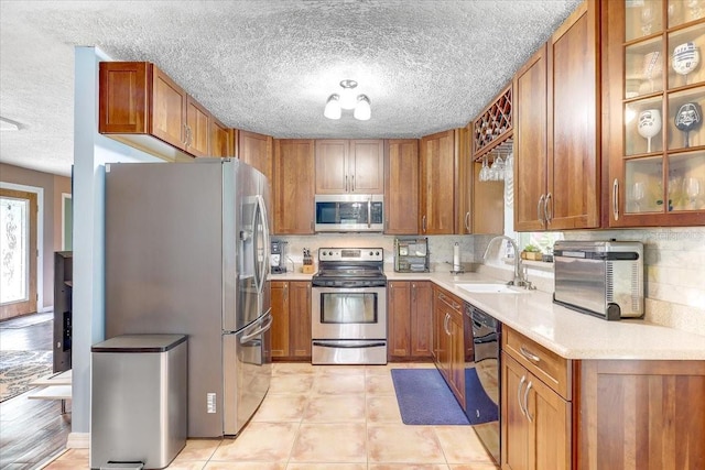 320 Pheasant Cir, Brandon, FL 33510 - kitchen featuring appliances with stainless steel finishes, plenty of natural light, brown cabinetry, and a textured ceiling