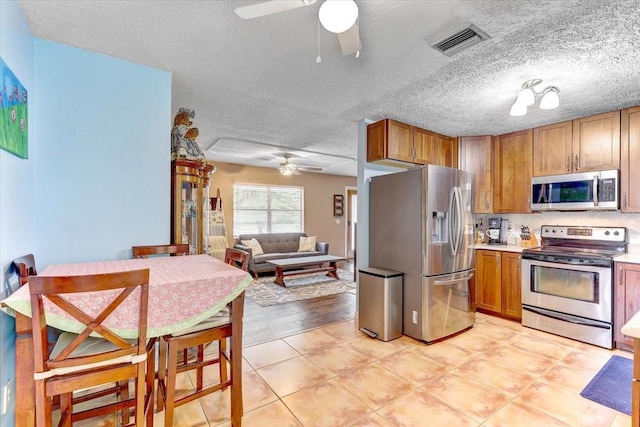 320 Pheasant Cir, Brandon, FL 33510 - kitchen featuring stainless steel appliances, a ceiling fan, brown cabinets, a textured ceiling, and light countertops