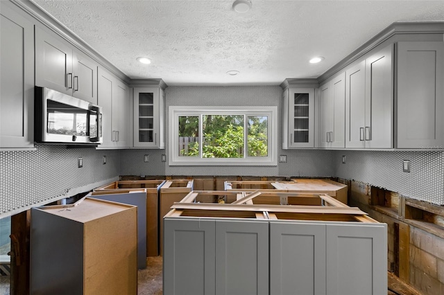 163 Barbados Ave, Tampa, FL 33606 - kitchen featuring stainless steel microwave, gray cabinets, recessed lighting, glass insert cabinets, and decorative backsplash