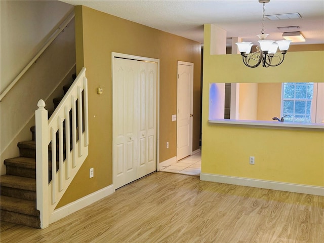 1212 Kennewick Ct, Wesley Chapel, FL 33543 - spare room with stairway, light wood finished floors, and a chandelier