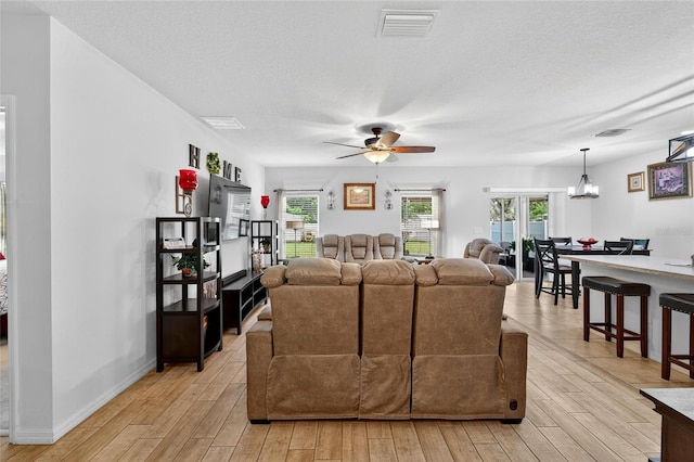 10409 Candleberry Woods Ln, Gibsonton, FL 33534 - living area with light wood-style floors, a textured ceiling, a ceiling fan, and plenty of natural light