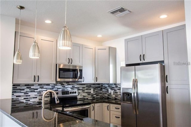 669 Lake Shore Pkwy, Davenport, FL 33896 - kitchen featuring stainless steel appliances, dark stone countertops, tasteful backsplash, decorative light fixtures, and a peninsula