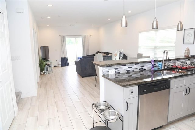 669 Lake Shore Pkwy, Davenport, FL 33896 - kitchen with stainless steel dishwasher, tasteful backsplash, dark stone countertops, open floor plan, and hanging light fixtures