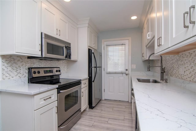 208 Danube Ave Unit 204, Tampa, FL 33606 - kitchen featuring stainless steel appliances, white cabinets, recessed lighting, backsplash, and light stone counters
