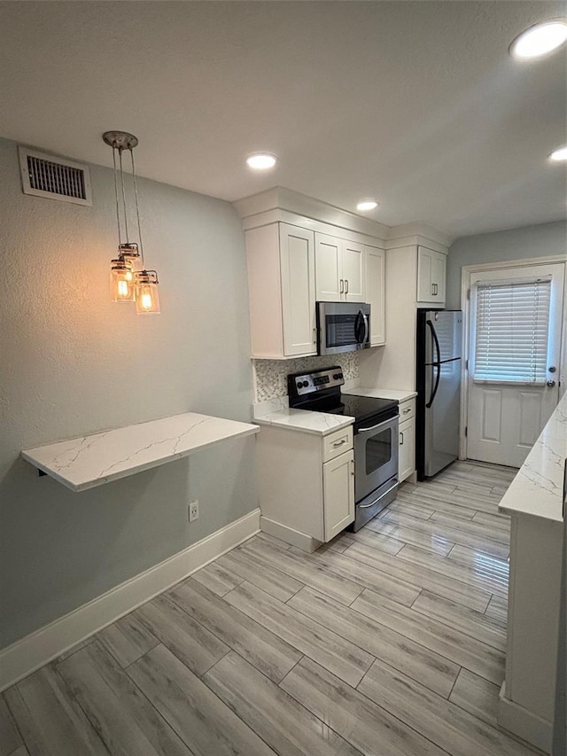 208 Danube Ave Unit 204, Tampa, FL 33606 - kitchen with stainless steel appliances, decorative backsplash, light wood-type flooring, white cabinetry, and pendant lighting