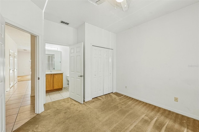 1713 Retreat Cir, Clermont, FL 34714 - unfurnished bedroom with light colored carpet, a closet, ensuite bath, light tile patterned flooring, and a ceiling fan