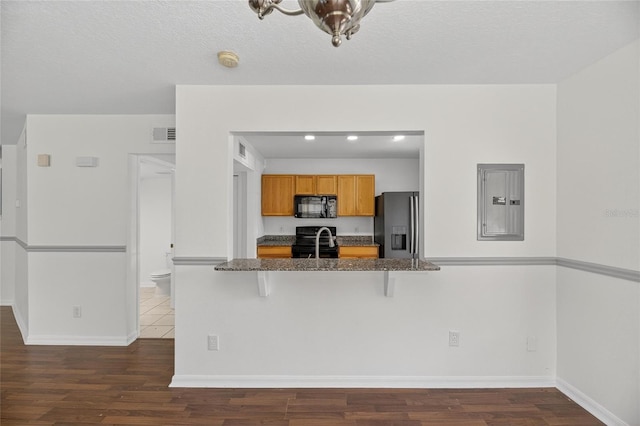 10737 Keys Gate Dr, Riverview, FL 33579 - kitchen with black appliances, electric panel, dark wood-style flooring, and a kitchen bar