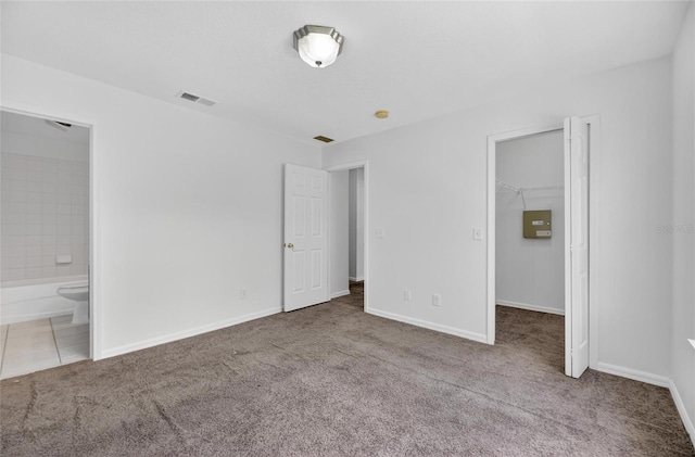 10737 Keys Gate Dr, Riverview, FL 33579 - unfurnished bedroom featuring carpet floors, a walk in closet, connected bathroom, and tile patterned floors