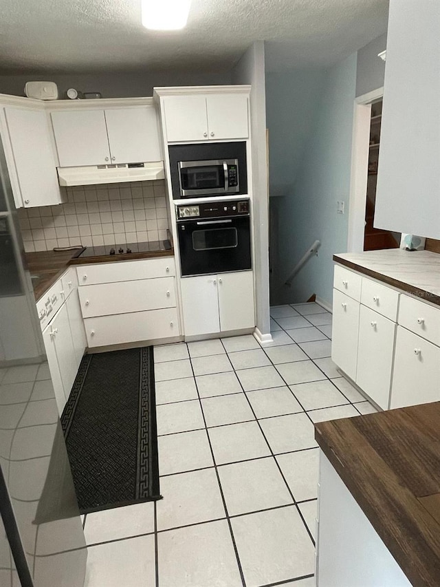 408 Blueberry Ln, Brandon, FL 33510 - kitchen with black appliances, under cabinet range hood, light tile patterned flooring, a textured ceiling, and white cabinetry
