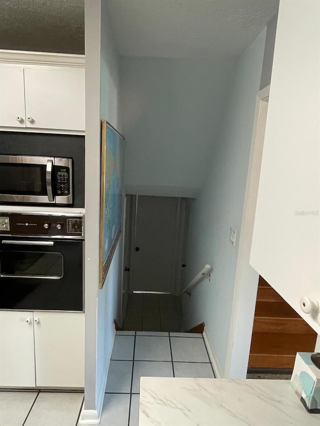 408 Blueberry Ln, Brandon, FL 33510 - kitchen with black oven, stainless steel microwave, tile patterned flooring, and white cabinetry