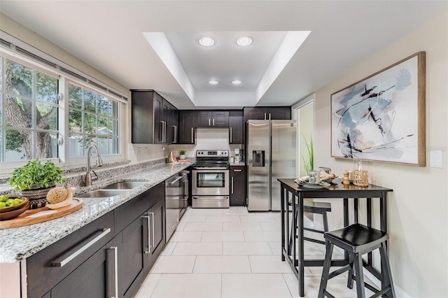 13521 Del Prado Dr S, Largo, FL 33774 - kitchen with stainless steel appliances, light stone counters, a tray ceiling, light tile patterned floors, and recessed lighting