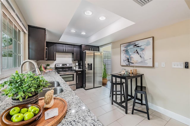 13521 Del Prado Dr S, Largo, FL 33774 - kitchen featuring stainless steel appliances, a tray ceiling, light stone countertops, recessed lighting, and light tile patterned floors