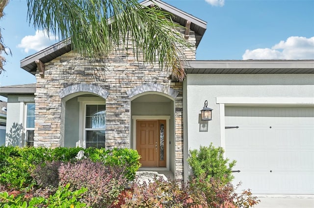 11713 Tetrafin Dr, Riverview, FL 33579 - doorway to property with stone siding, an attached garage, and stucco siding