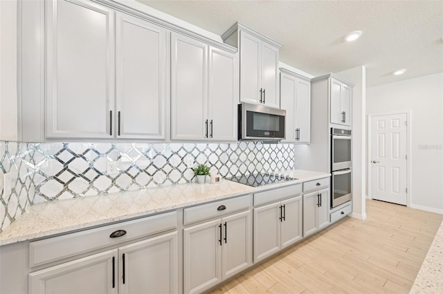 11713 Tetrafin Dr, Riverview, FL 33579 - kitchen with appliances with stainless steel finishes, backsplash, light wood-type flooring, light stone counters, and recessed lighting