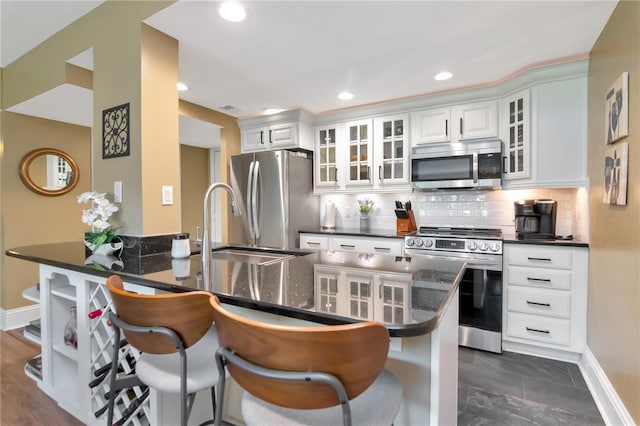 4141 Bayshore Blvd Unit 304, Tampa, FL 33611 - kitchen with stainless steel appliances, a breakfast bar area, tasteful backsplash, white cabinetry, and recessed lighting