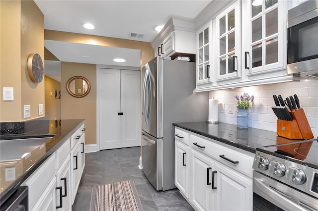 4141 Bayshore Blvd Unit 304, Tampa, FL 33611 - kitchen with appliances with stainless steel finishes, white cabinets, tasteful backsplash, dark stone countertops, and glass insert cabinets