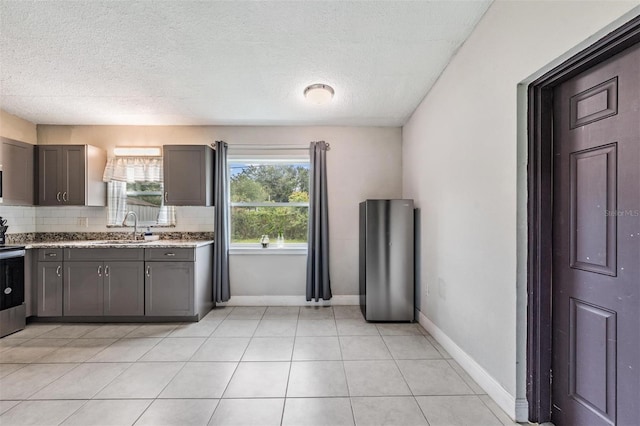 15008 Spokane Rd, Spring Hill, FL 34610 - kitchen featuring stainless steel stove, tasteful backsplash, a textured ceiling, gray cabinetry, and light tile patterned floors