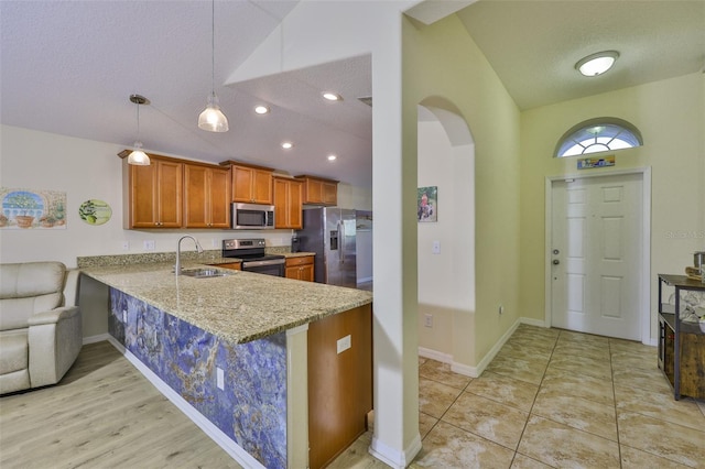 15403 Fire Rock Pl, Ruskin, FL 33573 - kitchen with stainless steel appliances, vaulted ceiling, light stone countertops, brown cabinetry, and a peninsula