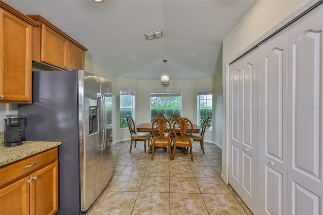 15403 Fire Rock Pl, Ruskin, FL 33573 - kitchen with stainless steel refrigerator with ice dispenser, brown cabinets, light stone counters, light tile patterned floors, and a textured ceiling