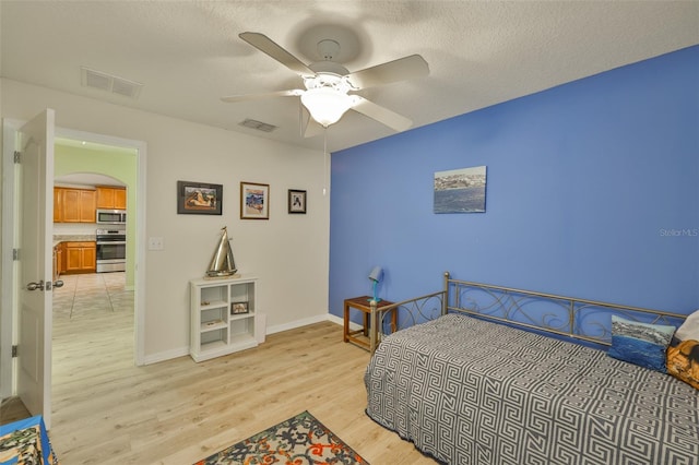 15403 Fire Rock Pl, Ruskin, FL 33573 - bedroom with light wood-type flooring, arched walkways, a textured ceiling, and a ceiling fan