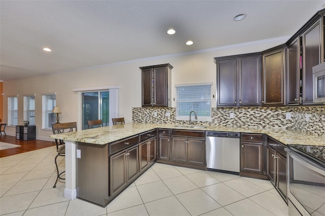 2605 Stardale Way, Lutz, FL 33558 - kitchen featuring appliances with stainless steel finishes, light tile patterned flooring, a peninsula, a kitchen bar, and light stone countertops