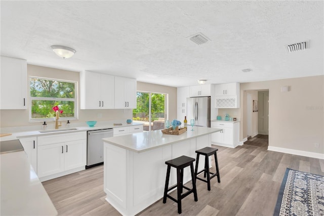 4723 Bloomingdale Ave, Valrico, FL 33596 - kitchen with stainless steel appliances, a kitchen breakfast bar, a kitchen island, light wood finished floors, and a textured ceiling