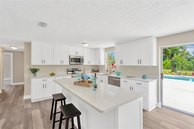 4723 Bloomingdale Ave, Valrico, FL 33596 - kitchen featuring appliances with stainless steel finishes, a textured ceiling, light countertops, light wood-style floors, and a center island