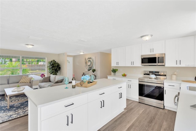 4723 Bloomingdale Ave, Valrico, FL 33596 - kitchen with appliances with stainless steel finishes, light wood-style floors, light countertops, open floor plan, and a kitchen island