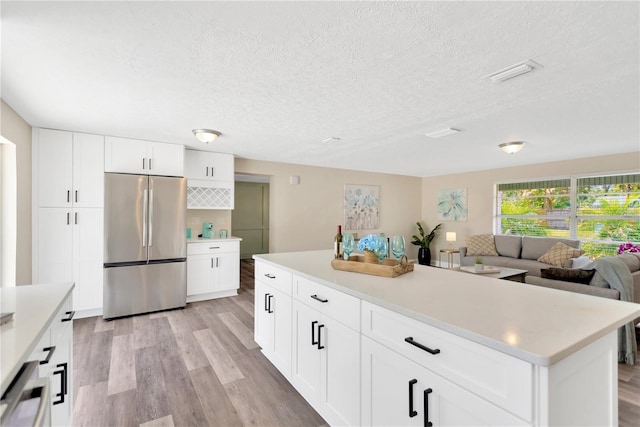 4723 Bloomingdale Ave, Valrico, FL 33596 - kitchen with freestanding refrigerator, light wood-type flooring, a textured ceiling, light countertops, and white cabinets