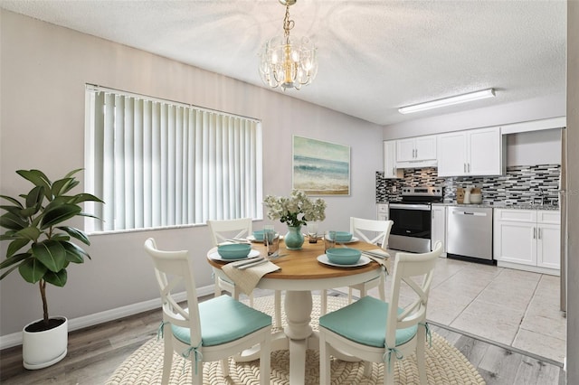 923 April Hills Blvd, Lady Lake, FL 32159 - dining room with a chandelier, a textured ceiling, and light wood finished floors