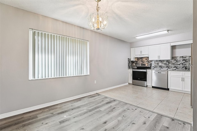 923 April Hills Blvd, Lady Lake, FL 32159 - kitchen featuring stainless steel appliances, a textured ceiling, a chandelier, white cabinetry, and tasteful backsplash