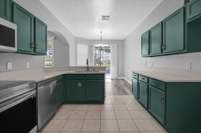 320 Tupelo Cir, Davenport, FL 33897 - kitchen featuring stainless steel appliances, green cabinetry, light countertops, a textured ceiling, and a peninsula