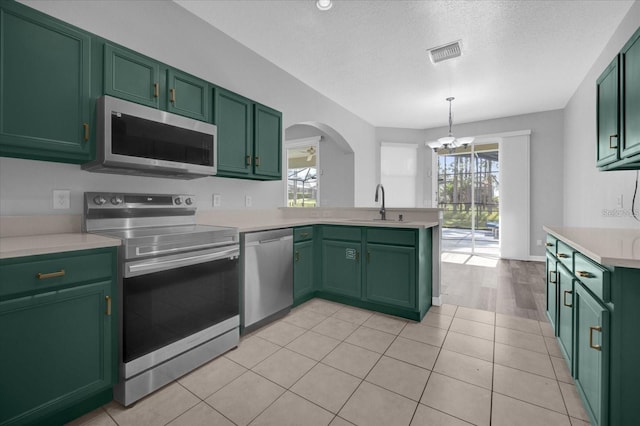 320 Tupelo Cir, Davenport, FL 33897 - kitchen with appliances with stainless steel finishes, green cabinetry, a chandelier, light countertops, and a peninsula