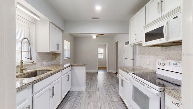 8609 N 11th St, Tampa, FL 33604 - kitchen with white appliances, tasteful backsplash, ceiling fan, white cabinets, and light stone countertops