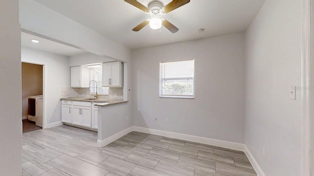 8609 N 11th St, Tampa, FL 33604 - kitchen featuring washer / clothes dryer, a ceiling fan, white cabinets, light stone counters, and backsplash