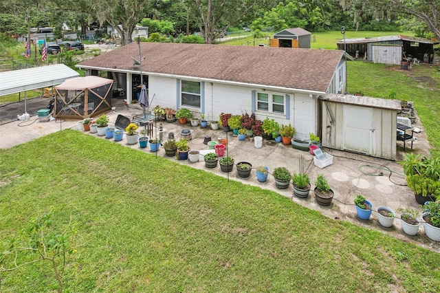 127 Locke Rd, Davenport, FL 33837 - rear view of house featuring a storage unit, a patio, roof with shingles, a lawn, and a gazebo