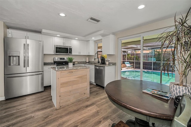 6053 11th Ave, New Port Richey, FL 34653 - kitchen with appliances with stainless steel finishes, white cabinetry, a center island, dark wood-type flooring, and recessed lighting