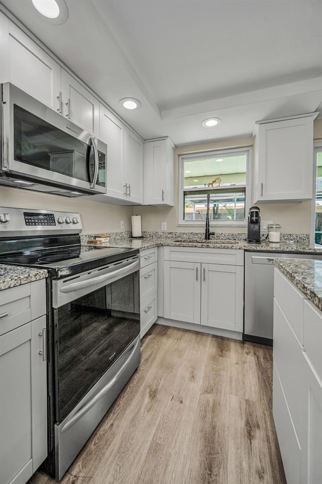 6053 11th Ave, New Port Richey, FL 34653 - kitchen featuring stainless steel appliances, light wood-style floors, recessed lighting, white cabinetry, and light stone counters